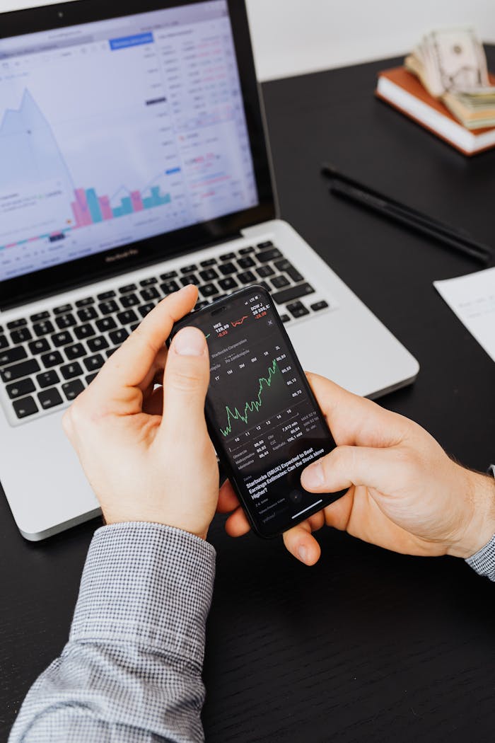 our-story Close-up of hands examining stock market graphs on smartphone and laptop.