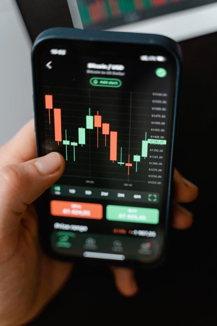 services-01 Hand holding smartphone displaying cryptocurrency trading graph in app.