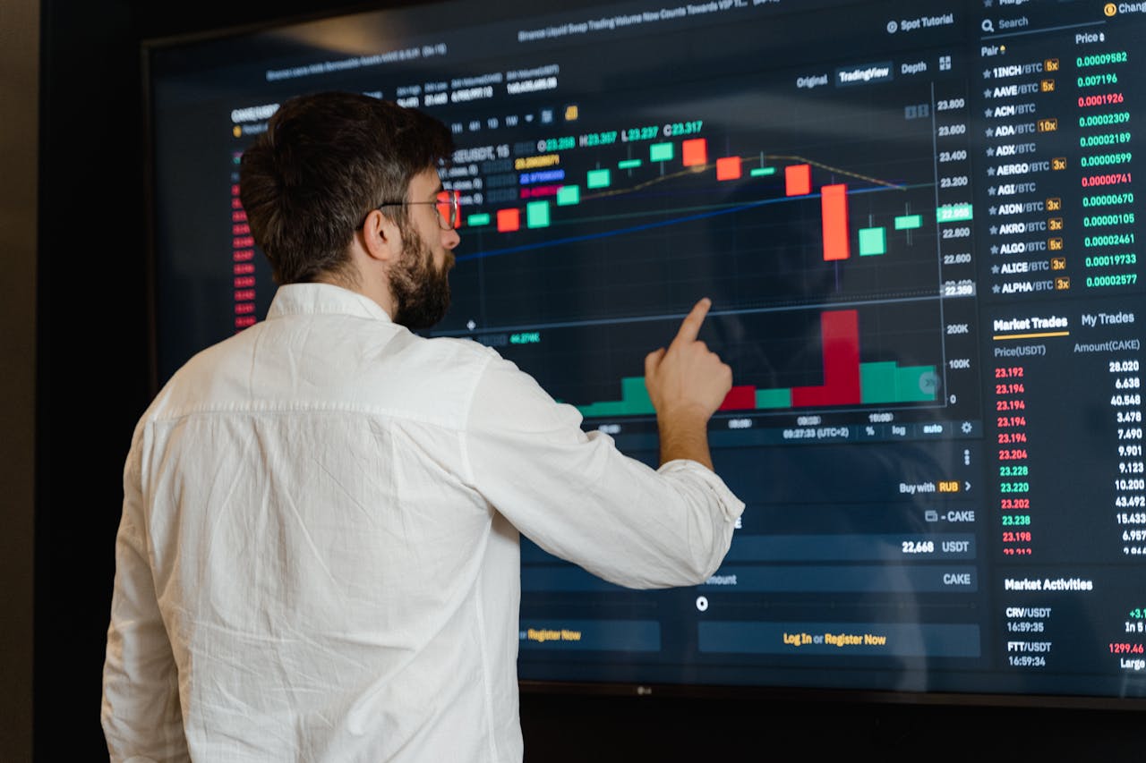 about-bg A man analyzes cryptocurrency graphs on a touchscreen monitor in a modern office setting.